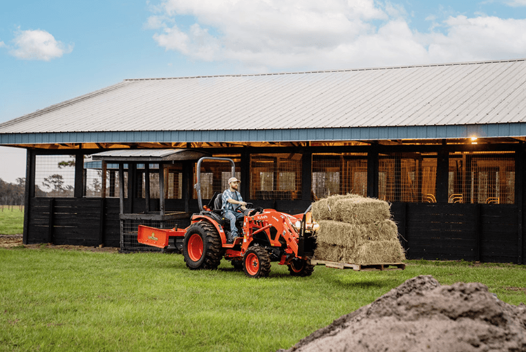 Man driving a tractor with stack of hay