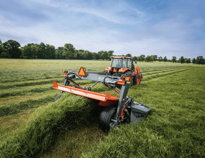Tractor using hay tool mowing implement 