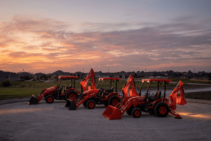 Kubota lineup of Tractor Loader Backhoes with a sunset