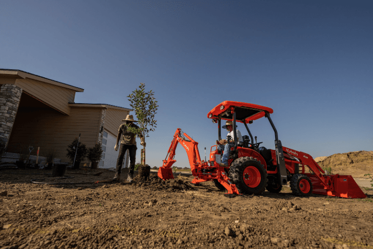 Landscaper using backhoe implement