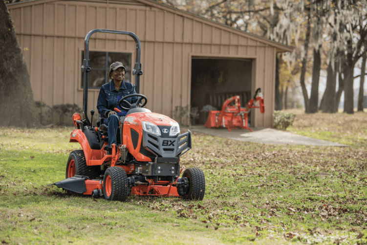 Woman driving a Kubota BX23S subcompact tractor