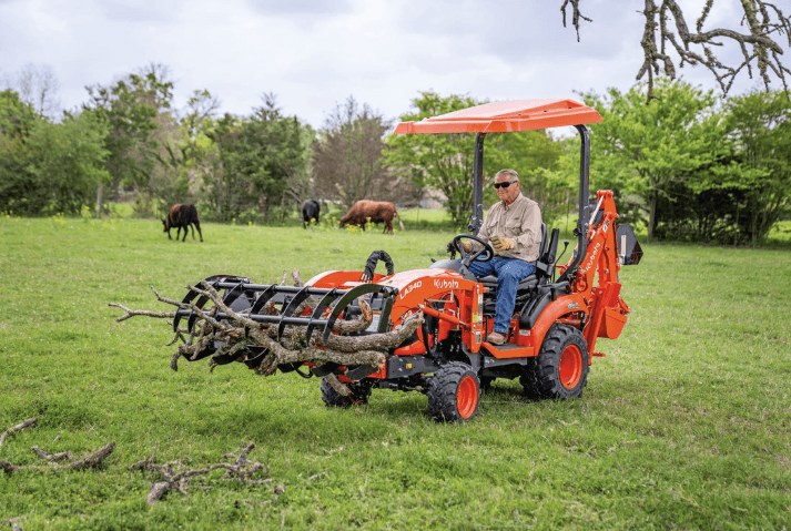 Man moving branches with a Kubota BX23S tractor