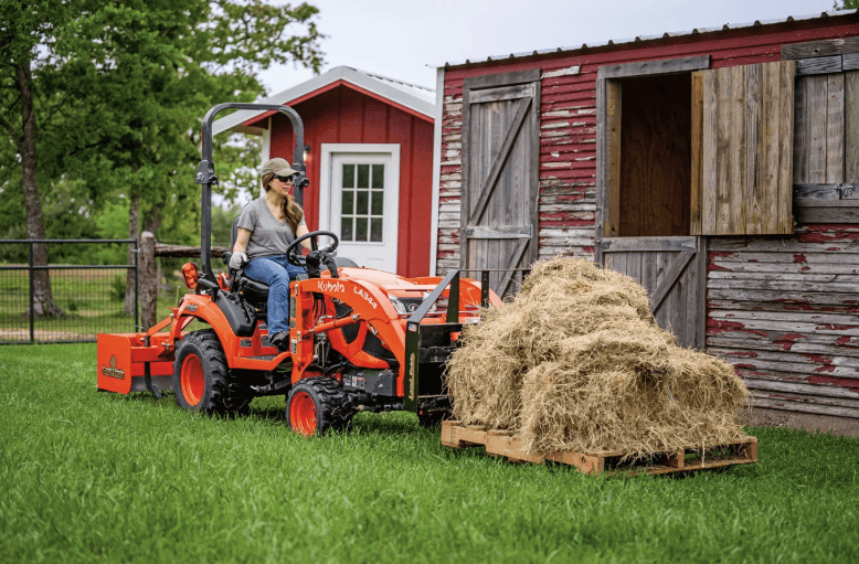 Woman moving pallet of hay stacks