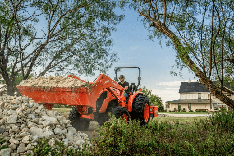 Man using tractor to dump rocks onto pile
