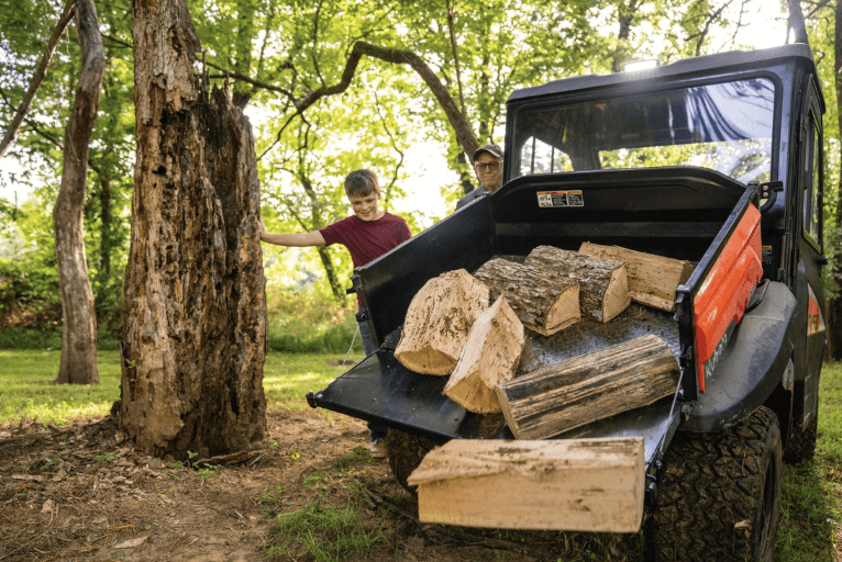 Adult and child using hydraulic cargo bed to dump firewood
